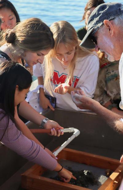 Students on a boat looking at catch